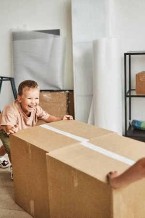 Portrait of two happy boys moving boxes and playing while family relocating to new house, copy space